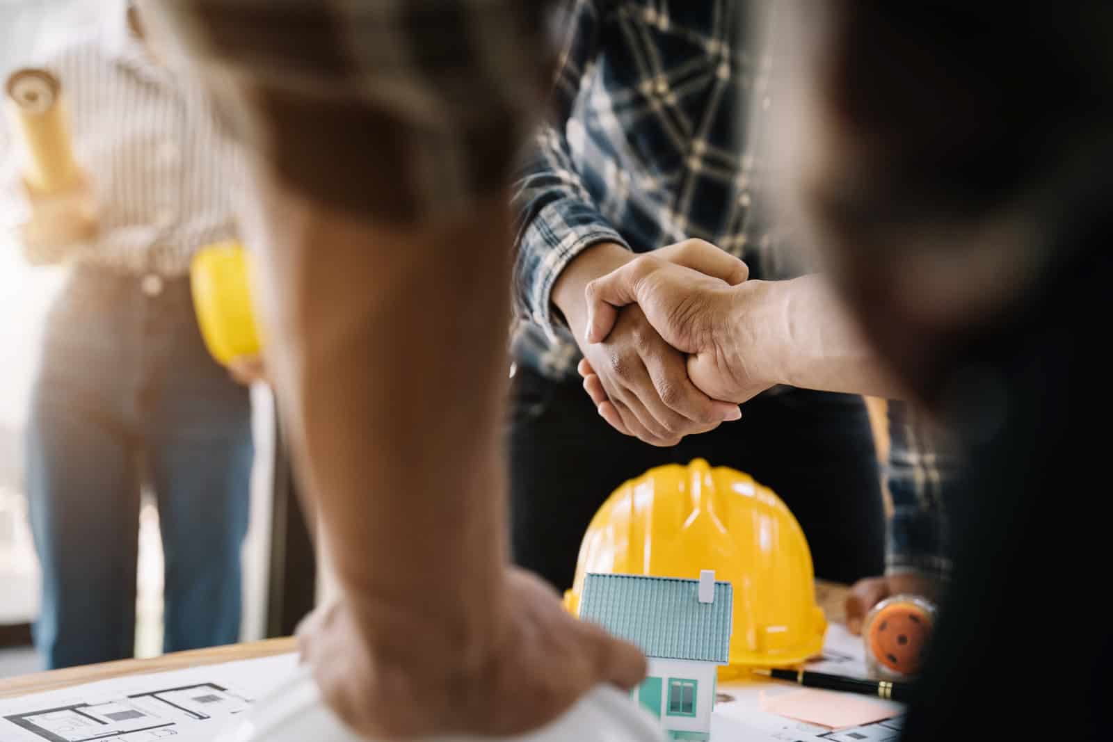 construction workers, architects and engineers shake hands while working for teamwork and cooperation after completing an agreement in an office facility, successful cooperation concept.